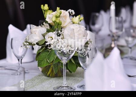 Beautiful white flower bouquets with drinking glasses at Wedding table setting Stock Photo