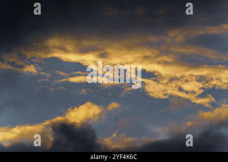 Stunning fluffy thunderstorm clouds illuminated by disappearing rays at sunset and dark thunderclouds floating across sunny blue sky to change season Stock Photo