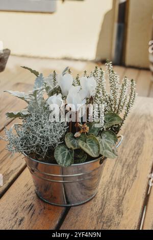 Flower composition. Bouquet of dried plants, flowers or leaves in a small bucket vase on old wooden table Stock Photo