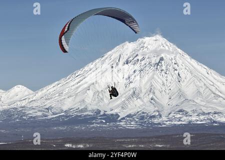 KAMCHATKA PENINSULA, RUSSIA, NOVEMBER 21, 2014: Paraglider flying on the background of the active Koriaksky Volcano (Koryaksky Volcano) on a sunny day Stock Photo