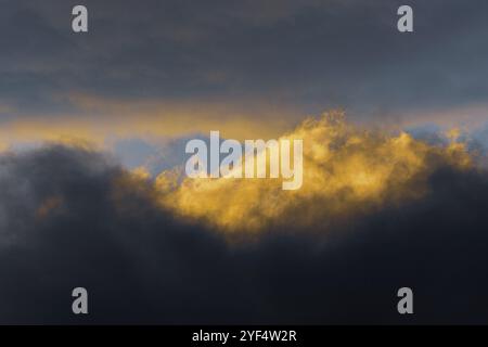 Fluffy clouds illuminated by disappearing rays at sunset and dark thunderclouds floating across sunny blue sky to change season weather. Stunning view Stock Photo