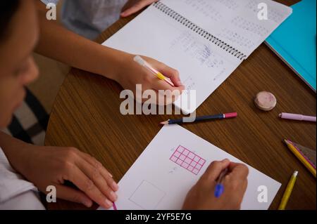 Top view of students working together on math homework, using pencils and graph paper. Collaboration and education concept. Stock Photo