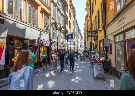 Tourists stroll along busy narrow street lined with colorful shops and historic buildings in Stockholm's Old Town. Stockholm. Sweden. Stock Photo