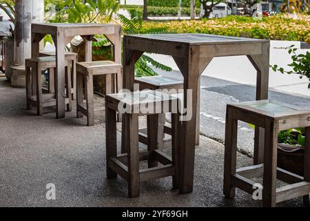 Outdoor cafe with wooden tables, stools on a city street. Wooden tables, stools, and chairs set up at an outdoor cafe on a sunny summer day. A cozy ou Stock Photo
