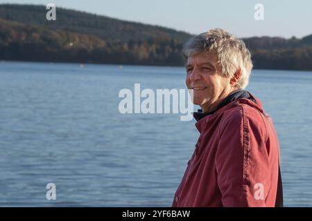 A happy, smiling senior citizen by a lake Stock Photo