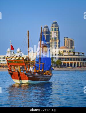 This photo captures a traditional Qatari dhow, adorned with the Argentine flag, sailing in front of the Corniche Fan Zone during the Qatar FIFA World Stock Photo