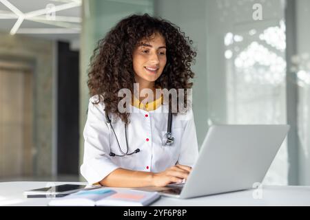 A hospital employee wears a lab coat with the words “healthcare worker ...