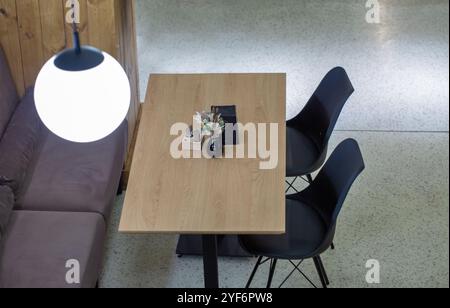 An empty table in a cafe with a sofa and two chairs awaits visitors. View from above. Stock Photo