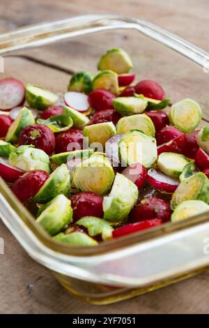 Brussels sprouts and radishes with some oil in a baking dish, ready to be roasted. Stock Photo