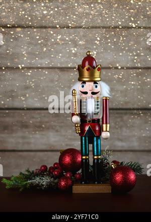 Christmas concept background. Christmas wooden nutcracker toy soldier with christmas balls and christmas lights on a dark table Stock Photo