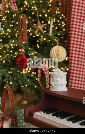 Close-up of a piano next to an illuminated Christmas tree with wrapped Christmas gifts Stock Photo