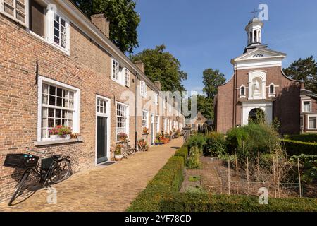 Beguinage in Breda with 29 houses around a herb garden with the Saint Catherine Church in the background. Stock Photo