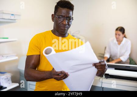 Technician african american working of printing house with stack of notebooks in her hands Stock Photo