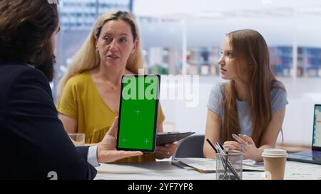 Financial adviser assisting clients in setting up investment accounts with green screen tablet, conducting audit. Consultant uses financial planning software on mockup device to help family, camera B Stock Photo