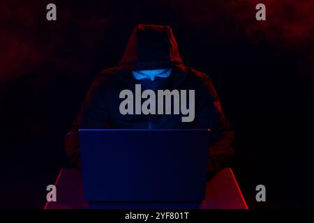 Computer Hacker in Hoodie. Obscured Dark Face. Hacker Attack, Virus Infected Software, Dark Web and Cyber Security Concept . Stock Photo