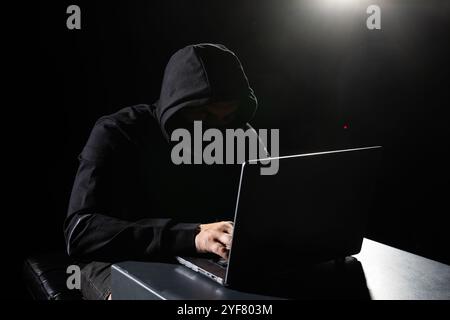 Computer Hacker in Hoodie. Obscured Dark Face. Hacker Attack, Virus Infected Software, Dark Web and Cyber Security Concept . Stock Photo