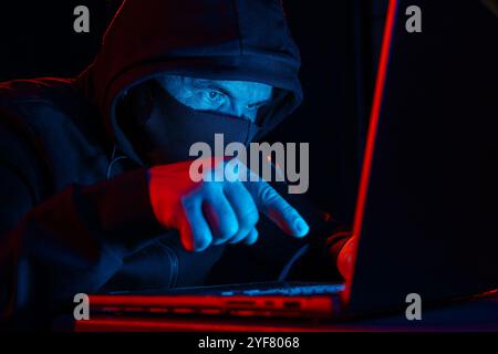 Computer Hacker in Hoodie. Obscured Dark Face. Hacker Attack, Virus Infected Software, Dark Web and Cyber Security Concept . Stock Photo