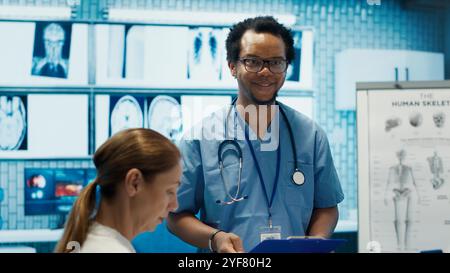 Licensed nurse specialist meeting with team for a research session, personalized medical services. Group of diverse healthcare professionals collaborating on treatment plans in a clinic. Camera A. Stock Photo