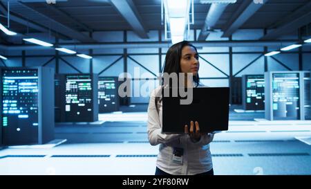 System administrator in data center monitoring security threats, implementing cybersecurity measures. Woman ensuring compliance with regulations to protect data center gear, camera B Stock Photo