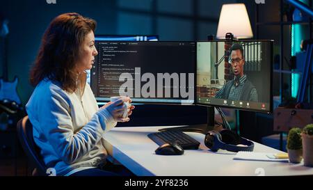 Software engineer teacher doing online tutoring, talking with student in online videocall about ways to do debugging. IT master teaching apprentice in webinar how to write code, camera A Stock Photo