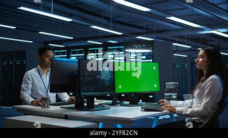 Technician doing checkup on green screen server hub PC to optimize it for data processing requirements of AI. Worker inspects data center used for machine learning using mockup computer, camera B Stock Photo