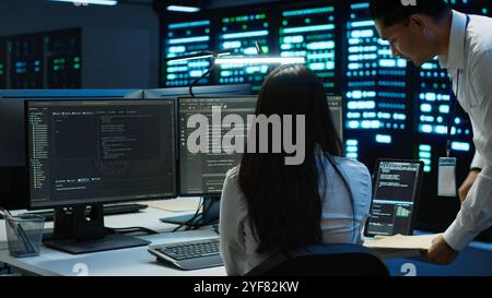 Team of programmers in data center responsible for installation and repair of networking equipment solving tasks. Teamworking colleagues doing maintenance on server room infrastructure, camera A Stock Photo
