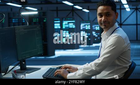 Portrait of upbeat admin in data center managing servers, operating systems and software programs. Joyous specialist in server hub ensuring networks are secure and functioning properly, camera A Stock Photo