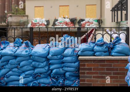 Protective barrier of blue sandbags stacked along building to shield property from flooding and rising waters Stock Photo