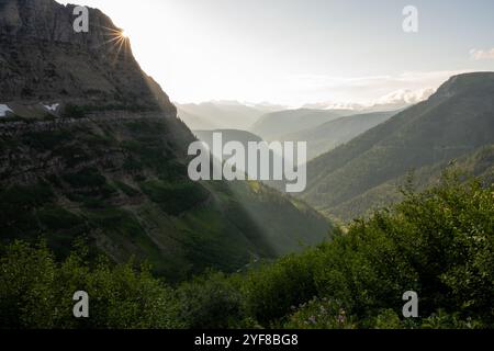 Sunburst and Shafts of Light Bend Around The Edge Of Mount Oberlin in Glacier National Park Stock Photo