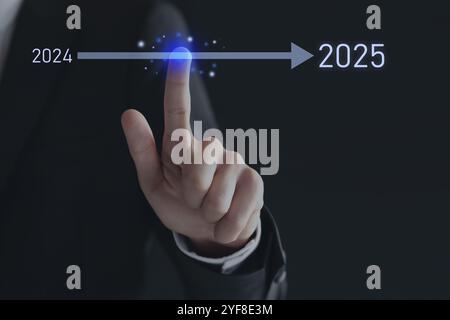 New year goals. Businessman touching arrow leading from 2024 to 2025 on virtual screen against black background, closeup Stock Photo