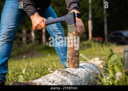 yong male in forest choping wood with steel axe close-up Stock Photo