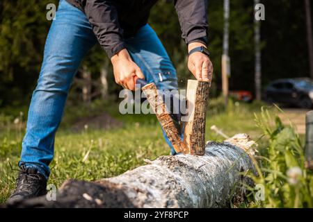 yong male in forest choping wood with steel axe close-up Stock Photo