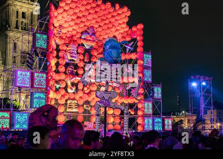 A vibrant Day of the Dead altar with illuminated decorations and skeletons lights up Zócalo at night, Mexico City. Dia de Muertos. Stock Photo