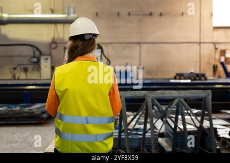 Rear view of an industrial woman engineer with smartphone in a factory, working Stock Photo