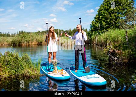 Young attractive couple on stand up paddle board in the lake, SUP Stock Photo