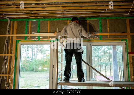Skilled worker installing windows in a new construction with exposed insulation and framing Stock Photo