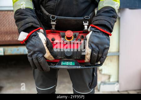 Close-up of Industrial Worker Operating a Remote Control Panel with Protective Gloves Stock Photo