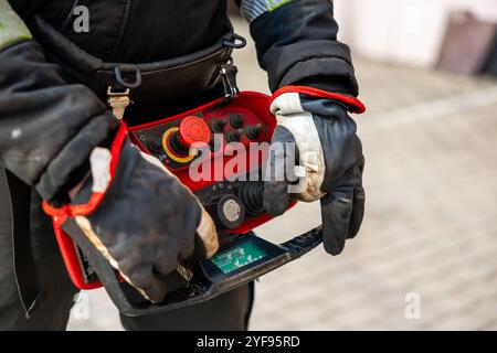 Close-up of Industrial Worker Operating a Remote Control Panel with Protective Gloves Stock Photo