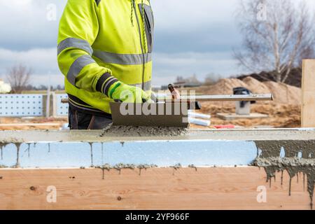 Focused Construction Worker Applying Smooth Finish to Fresh Concrete on Building Foundation Stock Photo