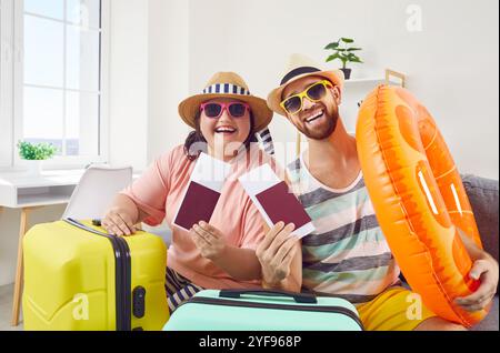 Happy couple of fat woman and smiling man in hats and sunglasses getting ready for holiday trip. Stock Photo