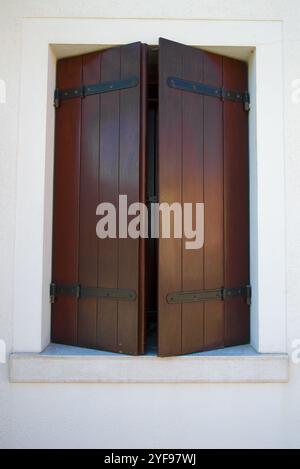 A half-open window with brown wooden shutters close-up. Venice, Italy Stock Photo