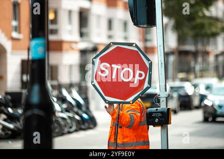 Road Construction Worker Holding a Stop Sign to Control Traffic Flow and Ensure Safety at Worksite Stock Photo