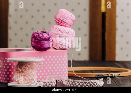 Neatly stored yarn and sewing products in a polka dot box on a black table, which evokes a sense of creativity and handicraft. Stock Photo