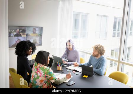 Male and female entrepreneurs discussing while sitting in conference room Stock Photo