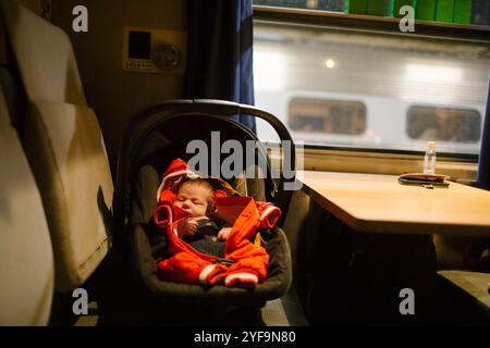 Boy sleeping inside baby seat in train Stock Photo