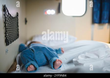 Boy with barefoot sleeping on bed in sleeper train Stock Photo