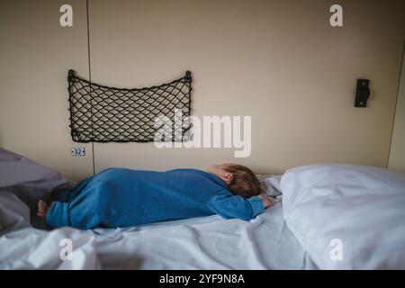 Side view of boy sleeping on bed in sleeper train Stock Photo