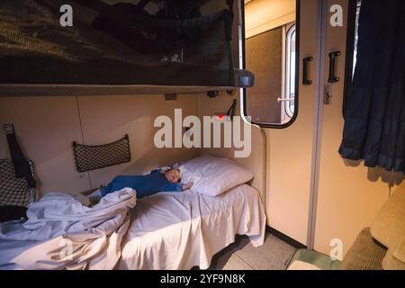 Toddler boy sleeping on bed in sleeper train Stock Photo