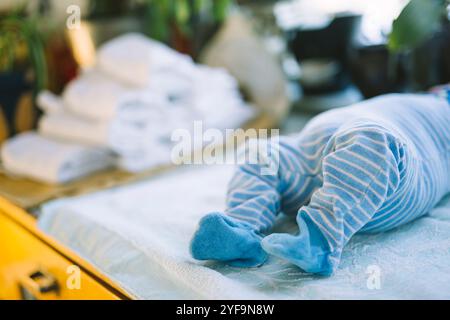 Baby in striped blue clothing lying down on table Stock Photo