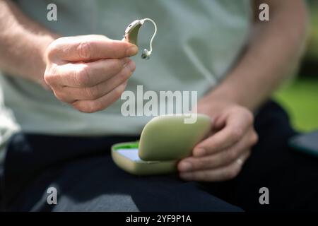 Close-up of man holding hearing aid device Stock Photo